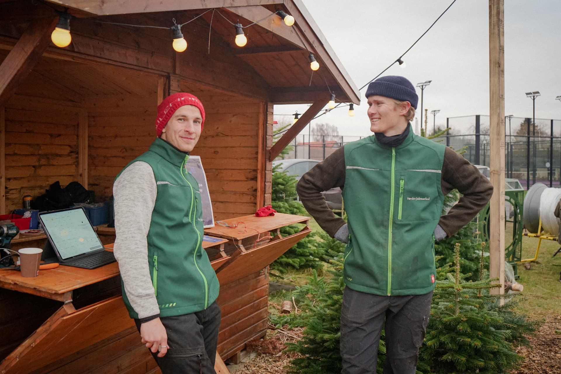 To medarbejdere i grønne Hørslev Julemarked-veste ved salgsboden